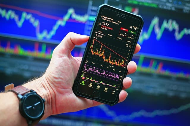 the man holds up a phone with a graph